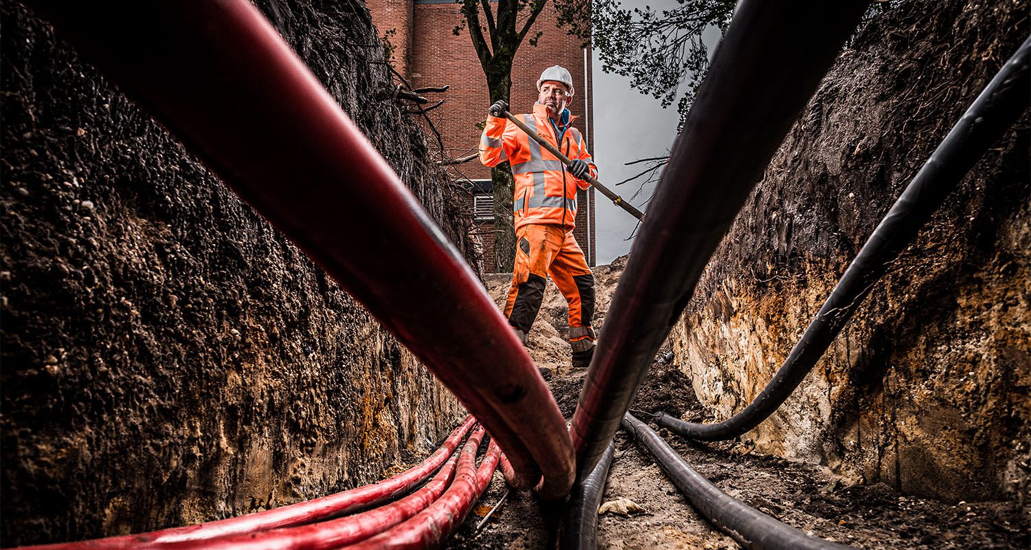 Een grondwerker aan het werk met leidingen en kabels.