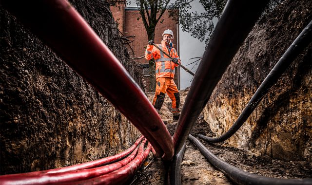 Een grondwerker aan het werk met leidingen en kabels.