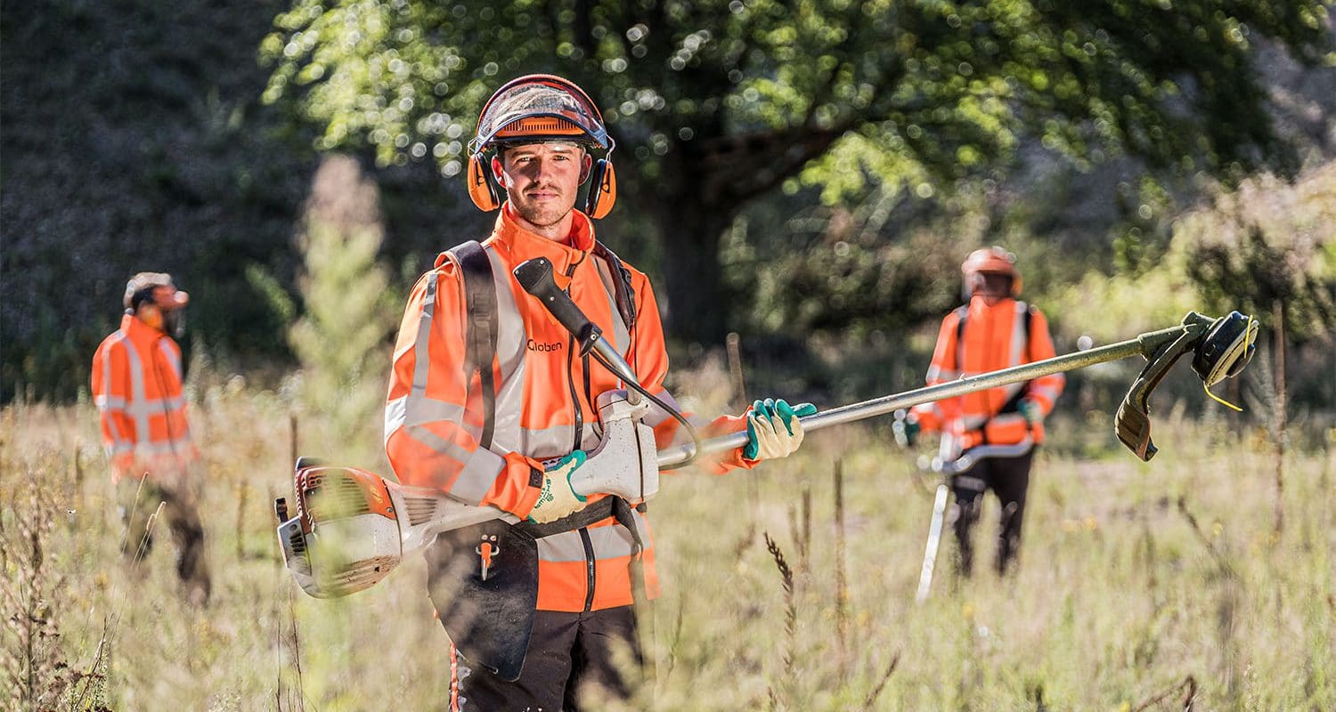 Een meewerkend voorman met medewerkers groenvoorziening aan het werk.