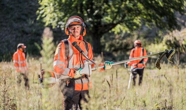 Een meewerkend voorman met medewerkers groenvoorziening aan het werk.