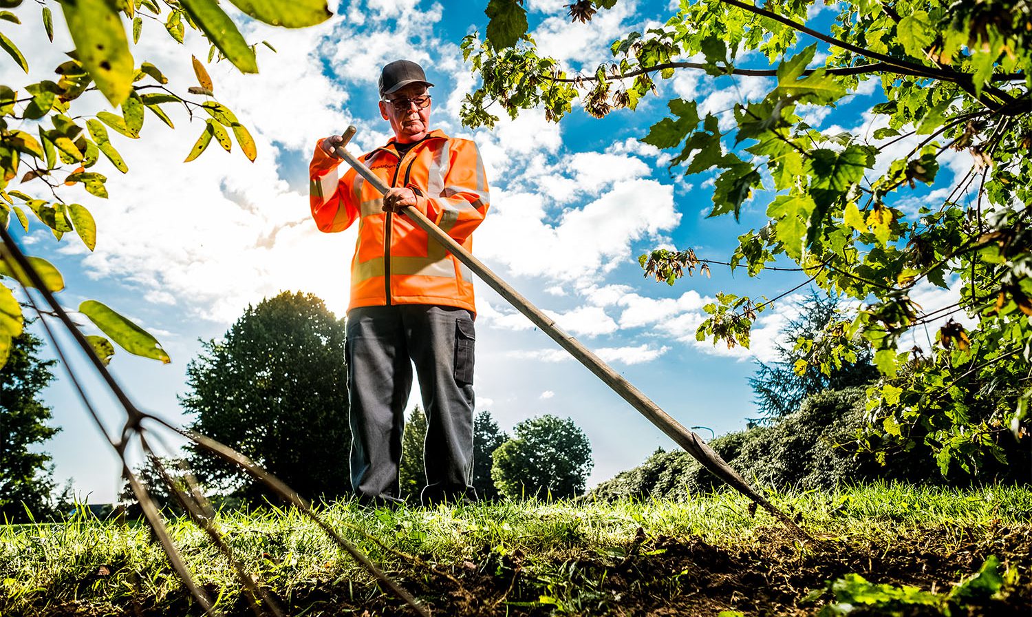 medewerker groenvoorziening aan het werk met een schoffel