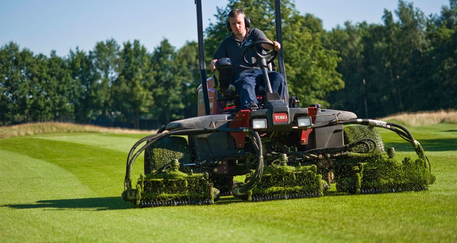 Greenkeeper aan het grasmaaien