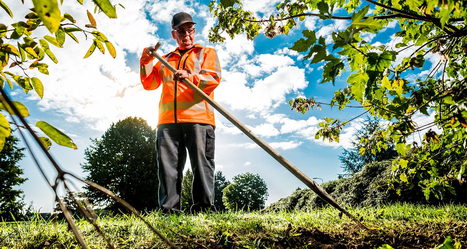 Medewerker groenvoorziening met de schoffel